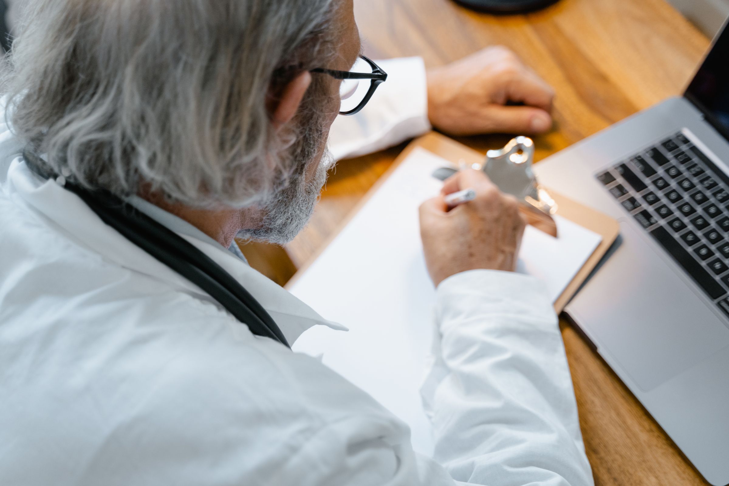 Illustrative photograph of a clinician using a laptop and writing notes
