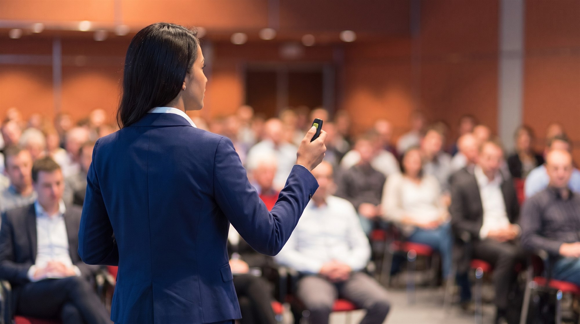A woman presenting to an audience at a conference